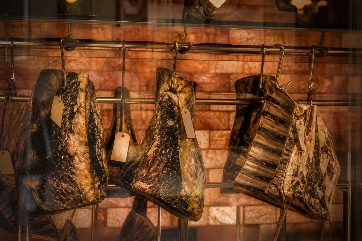 Cave de maturation vitrée avec quartiers de bœuf suspendus et étiquettes de date